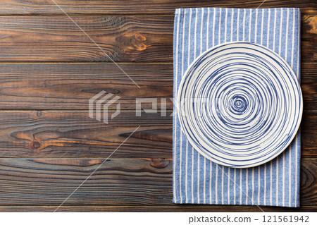 Top view on colored background empty round blue plate on tablecloth for food. Empty dish on napkin with space for your design 121561942