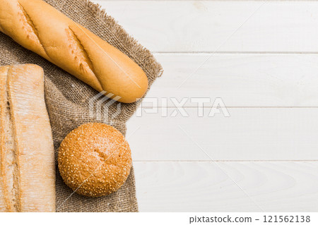 Assortment of freshly baked bread with napkin on rustic table top view. Healthy unleavened bread. French bread Assortment of freshly baked bread with napkin on rustic table top view. Healthy unleavened bread. French bread 121562138