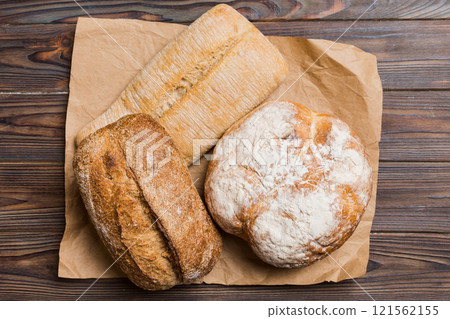 Assortment of freshly baked bread with napkin on rustic table top view. Healthy unleavened bread. French bread Assortment of freshly baked bread with napkin on rustic table top view. Healthy unleavened bread. French bread 121562155