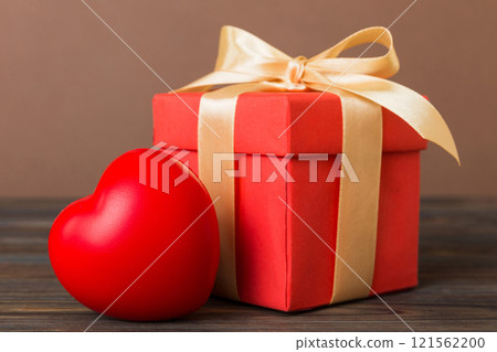 gift box with red bow and red heart on colored background. Perspective view. Flat lay gift box with red bow and red heart on colored background. Perspective view. Flat lay 121562200