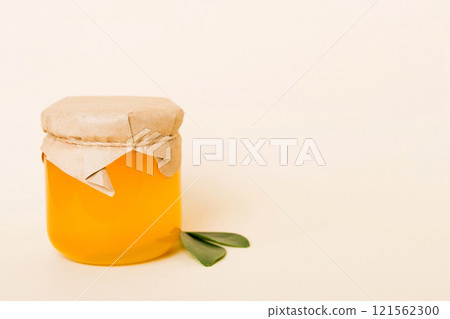 Honey in jar with leaves and honey dipper on colored background top view with copy text 121562300
