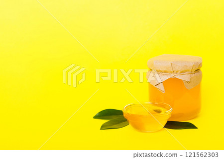 Honey in jar with leaves and honey dipper on colored background top view with copy text Honey in jar with leaves and honey dipper on colored background top view with copy text 121562303