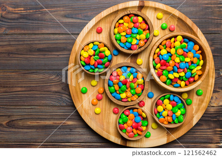 different colored round candy in bowl and jars. Top view of large variety sweets and candies with copy space different colored round candy in bowl and jars. Top view of large variety sweets and candies with copy space 121562462