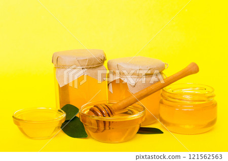 Honey in jar with leaves and honey dipper on colored background top view with copy text Honey in jar with leaves and honey dipper on colored background top view with copy text 121562563
