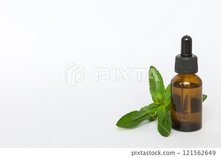 Natural Mint Essential Oil in a Glass Bottle. organic cosmetics with herbal extracts of mint on colored background 121562649