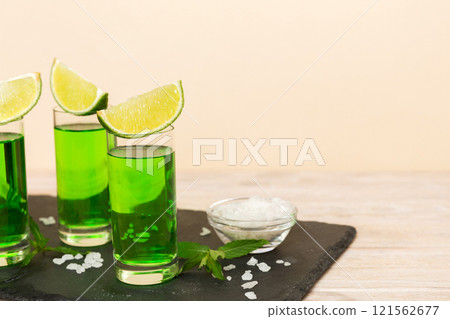 Sweet refreshing mint liqueur, with ice and mint leaves on table background, Shots with lime slice and mint flat lay 121562677