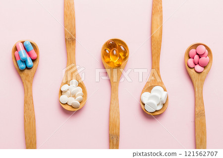 Vitamin capsules in a spoon on a colored background. Pills served as a healthy meal. Red soft gel vitamin supplement capsules on spoon Vitamin capsules in a spoon on a colored background. Pills served as a healthy meal. Red soft gel vitamin supplement capsules on spoon 121562707