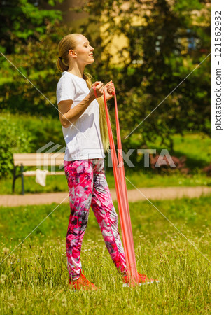 Girl doing exercises outdoor, using resistance fit band. Girl doing exercises outdoor, using resistance fit band. 121562932