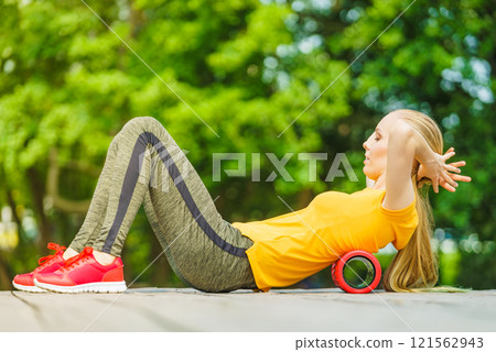 Girl doing exercises outdoor, using roller Girl doing exercises outdoor, using roller 121562943