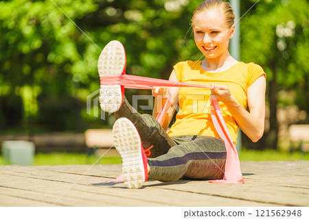 Girl doing exercise outdoor, using resistance fit band. Girl doing exercise outdoor, using resistance fit band. 121562948