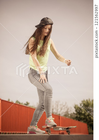 Teen girl skater riding skateboard on street. 121562997
