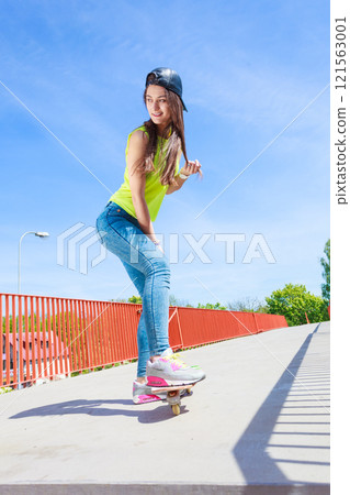 Teen girl skater riding skateboard on street. Teen girl skater riding skateboard on street. 121563001