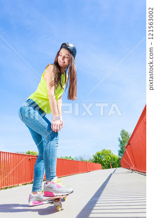 Teen girl skater riding skateboard on street. 121563002