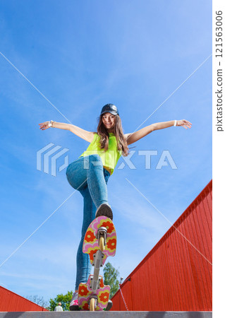Teen girl skater riding skateboard on street. 121563006