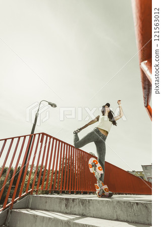 Teen girl skater riding skateboard on street. Teen girl skater riding skateboard on street. 121563012