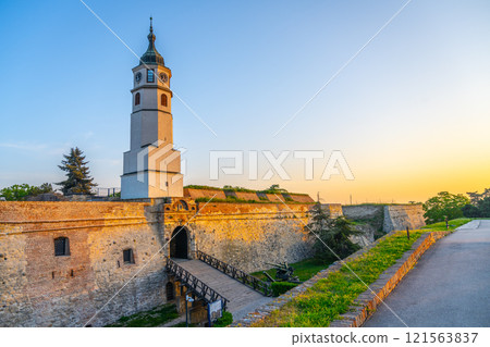 As the sun sets over Belgrade, the Clock Tower and Clock Gate at Kalemegdan Fortress illuminate the historic site, highlighting its ancient architecture and serene surroundings. 121563837