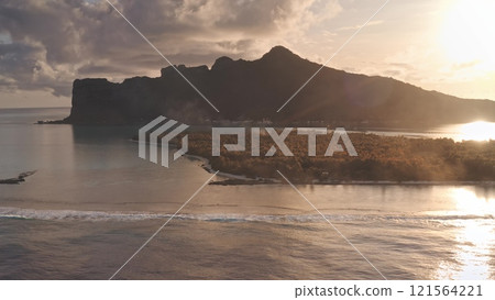 Golden sunset over Maupiti tropical island, French Polynesia. Barrier reef waves breaking shore, mount Teurafaatui silhouette in the background. Remote wild nature summer vacation travel. Aerial shot 121564221