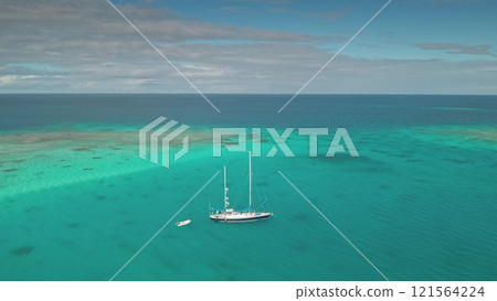 Breathtaking aerial drone view of sailboat white yacht anchored near vibrant coral reef in turquoise water lagoon of south pacific ocean. Remote wild nature paradise, exotic summer travel background Breathtaking aerial drone view of sailboat white yacht anchored near vibrant coral reef in turquoise water lagoon of south pacific ocean. Remote wild nature paradise, exotic summer travel background 121564224