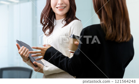 Two women/businesswomen standing and talking 121564248