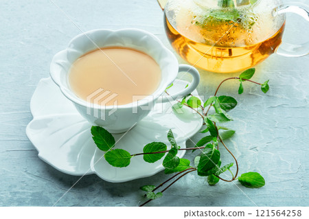 Mint tea. A cup of peppermint tea with fresh mint leaves and a tea pot 121564258