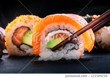 Sushi rolls on a black background. Uramaki with salmon and avocado 121564259