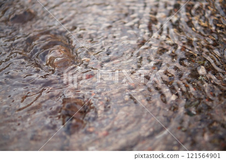 The camera captures a shallow stream of water flowing down the surface of the asphalt, forming small waves. Then it comes to a spring that bursts out of the ground, rising to the surface The camera captures a shallow stream of water flowing down the surface of the asphalt, forming small waves. Then it comes to a spring that bursts out of the ground, rising to the surface 121564901