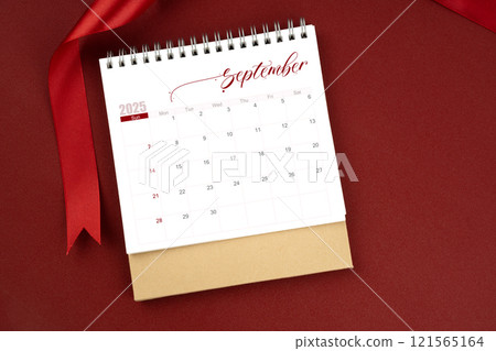 September 2025 desk calendar and red ribbon on red background. September 2025 desk calendar and red ribbon on red background. 121565164