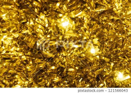 A close-up macro shot of golden tinsel with twinkling lights, creating a festive and sparkling background. A close-up macro shot of golden tinsel with twinkling lights, creating a festive and sparkling background. 121566043