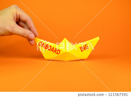 Onboarding success symbol. Concept word Onboarding on beautiful yellow paper boat. Beautiful orange background. Businessman hand. Business onboarding success concept. Copy space. 121567391