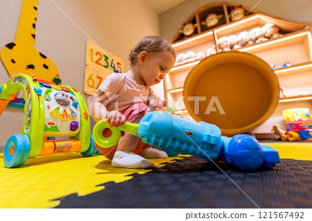 Child cleaning with a toy vacuum cleaner in a vibrant play area designed for imagination and motor skill development Child cleaning with a toy vacuum cleaner in a vibrant play area designed for imagination and motor skill development 121567492