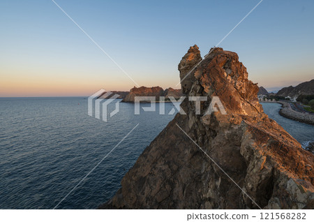 Sunset view of rocky coast of Muscat in Oman and calm ocean waters. 121568282