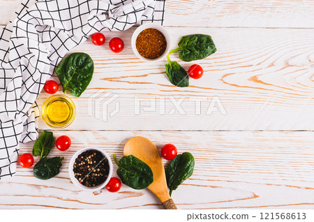 Spinach leaves, tomatoes, spices and oil on white wooden background top view 121568613