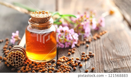Honey jar with cork and wildflowers on wooden surface. Rustic honey presentation. Concept of organic farming, countryside delights, and floral notes Honey jar with cork and wildflowers on wooden surface. Rustic honey presentation. Concept of organic farming, countryside delights, and floral notes 121568883
