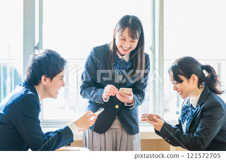 Male and female high school students talking while looking at their classmates and smartphones in the classroom 121572705