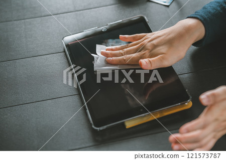 一位女士擦拭平板電腦設備的螢幕 121573787