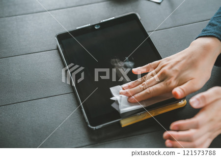 A woman wiping the screen of a tablet device A woman wiping the screen of a tablet device 121573788