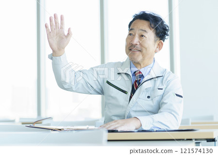 穿著工作服的中年男子在研討會上舉手攝影合作：電波學園教育法人東京電子學校 121574130
