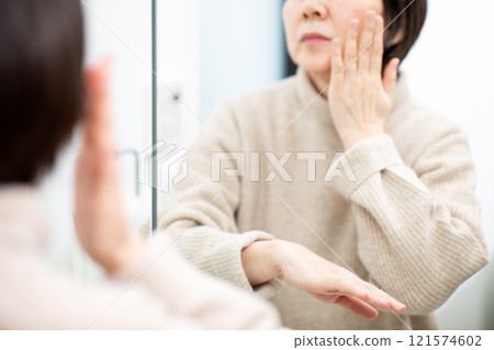 中高級女性一邊照浴室鏡子一邊做皮膚護理 121574602