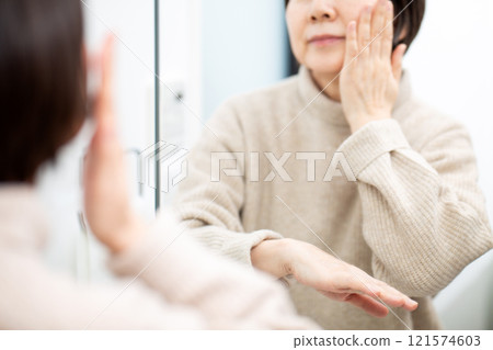 中高級女性一邊照浴室鏡子一邊做皮膚護理 121574603