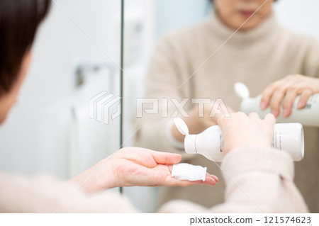 Middle-aged to senior women doing skin care while looking at the bathroom mirror Middle-aged to senior women doing skin care while looking at the bathroom mirror 121574623