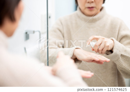 Middle-aged to senior women doing skin care while looking at the bathroom mirror 121574625