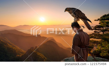 Epic moment man holds falcon on his arm atop cliff Epic moment man holds falcon on his arm atop cliff 121575494