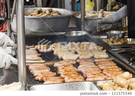 Close-up of the vendors grilling Taiwanese sausage and sticky rice (glutinous rice) sausage in the night market in Taiwan. This is one of the street snacks popular among tourists in Taiwan. 121575540