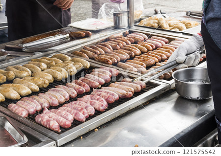 Close-up of the vendors grilling Taiwanese sausage and sticky rice (glutinous rice) sausage in the night market in Taiwan. This is one of the street snacks popular among tourists in Taiwan. 121575542