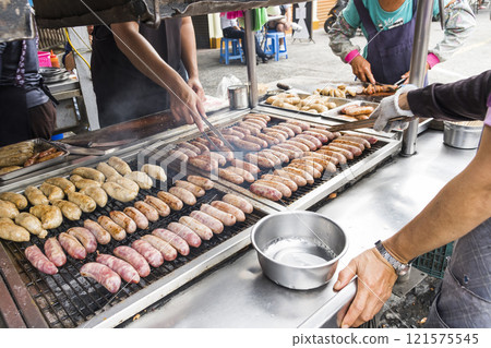 Close-up of the vendors grilling Taiwanese sausage and sticky rice (glutinous rice) sausage in the night market in Taiwan. This is one of the street snacks popular among tourists in Taiwan. 121575545