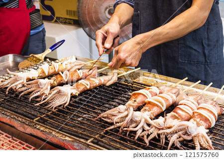Close-up of the vendors grilling squid skewers at the night market in Taiwan.  121575760