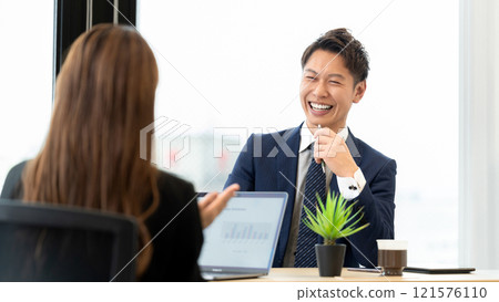 Two businessmen, a man and a woman, having a meeting using a computer Two businessmen, a man and a woman, having a meeting using a computer 121576110