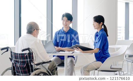 A caregiver explaining to an elderly person 121576610