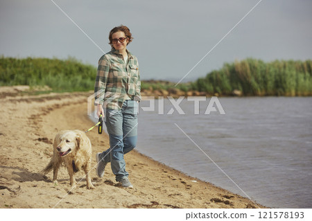 A beautiful woman walks with a dog near the sea in Denmark 121578193