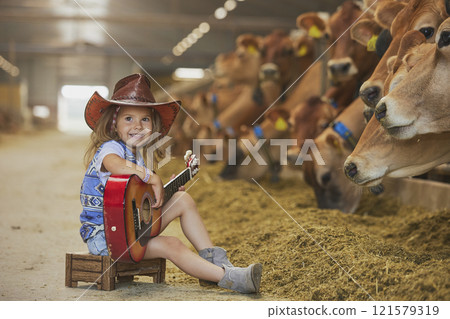 Charming child in a cowboy costume sings for cows on a farm in Denmark 121579319